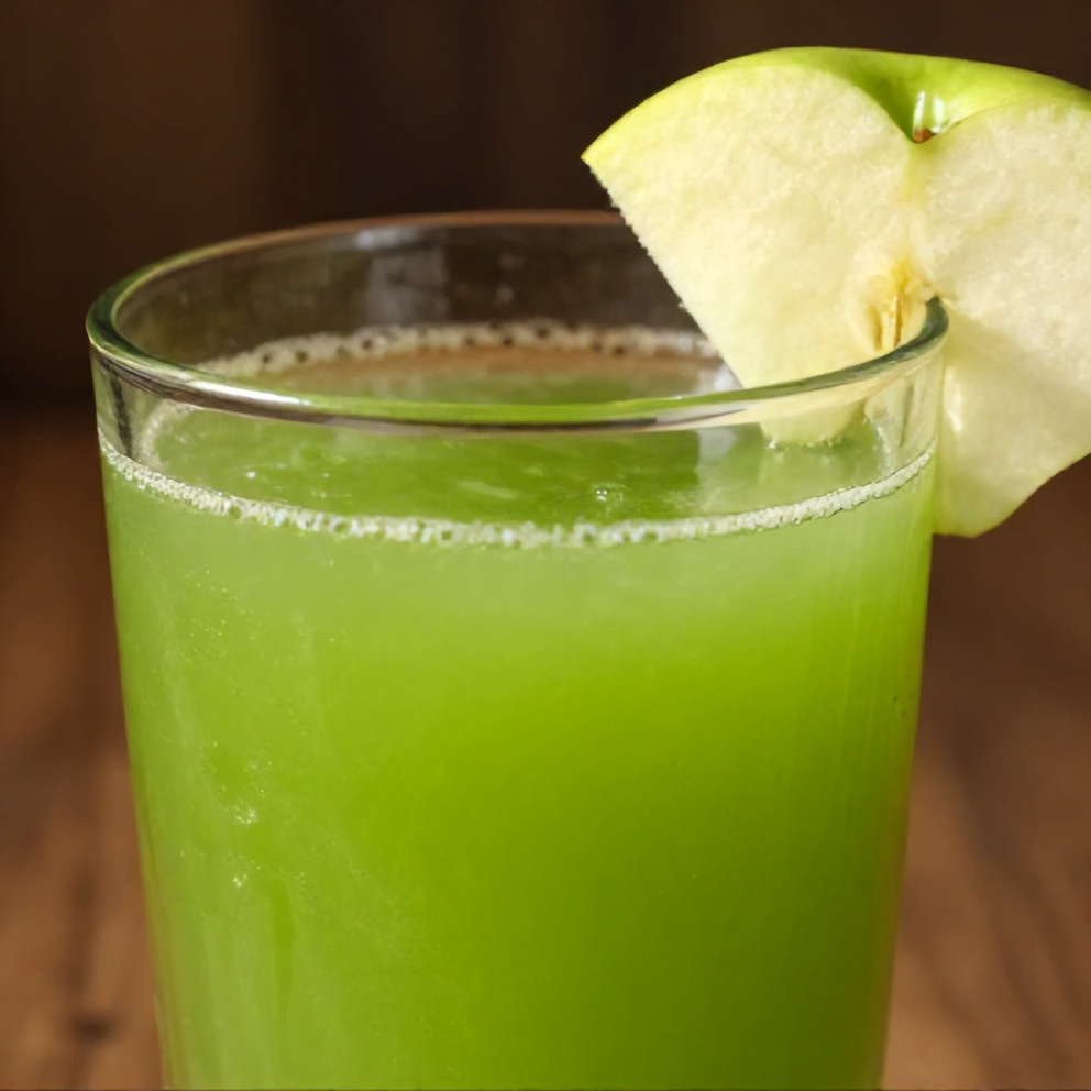 Glass of celery apple juice with a slice of apple on the rim