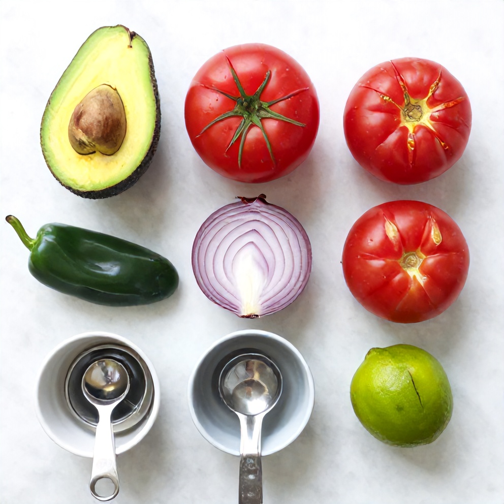 Avocado, tomatoes, red onion, jalapeño, cilantro, lime, and olive oil arranged on a white marble surface